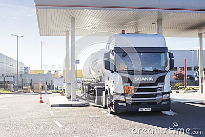 White fuel tanker truck at a petrol station connected by a hose to the underground tanks and refelling it. Editorial Stock Photo