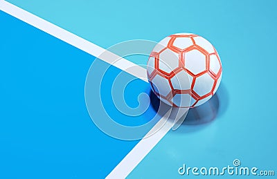 White futsal soccer ball with orange hexagon dropping shadow on the corner of a soccer field background Stock Photo