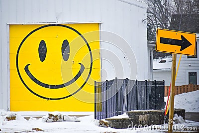 Garage with Yellow Smiley Face and a Street Sign Arrow Editorial Stock Photo