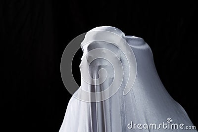 White ghost in white cloth on isolated black background. Face devil shouting covered curtain on blank. Halloween concept Stock Photo