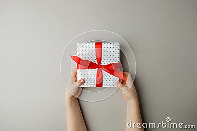 White gift box with red bow in the children`s hands on gray background, Shopping, sale, mother day, valentine, christmas Stock Photo