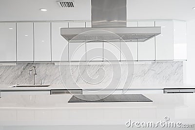 White glossy Kitchen with cooktop in Island and vent Stock Photo