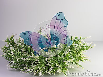 White and green floral wreath with a purple and blue mesh decorative butterfly with gemstones sitting on top with a white Stock Photo
