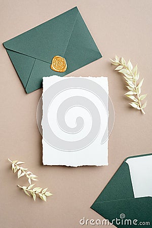 White and green wedding stationery set. Blank greeting card, craft envelope with wax seal stamp, dried flowers. Stock Photo