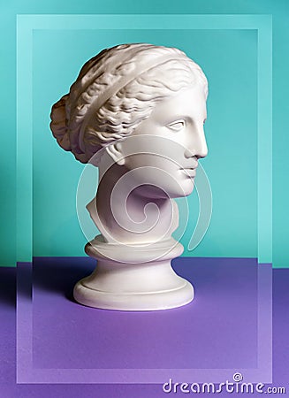 White gypsum copy of ancient statue Venus head on a green purple background. Plaster sculpture woman face. Stock Photo