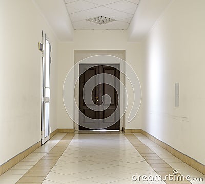 White hallway with marble floor and brown door Stock Photo