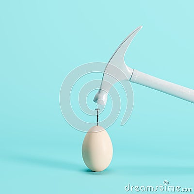 White hammer hitting on white egg on blue background Stock Photo