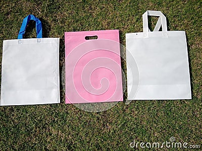 white handle loop bag with pink color d cut Eco friendly bags, non woven fabric bags on grass Stock Photo