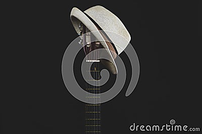 White hat hangs on the guitar fretboard. acoustic musical instrument. strings on the guitar neck Stock Photo