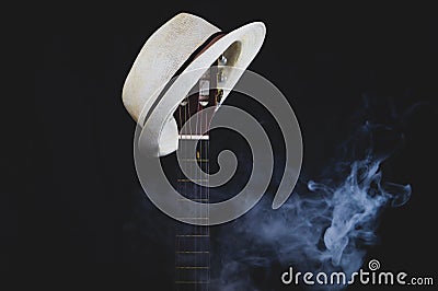 White hat hangs on the smoking guitar fretboard. acoustic musical instrument. strings on the guitar neck Stock Photo