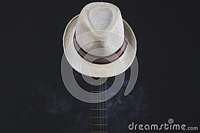 White hat in smoke hangs on the guitar fretboard. acoustic musical instrument. strings on the guitar neck Stock Photo