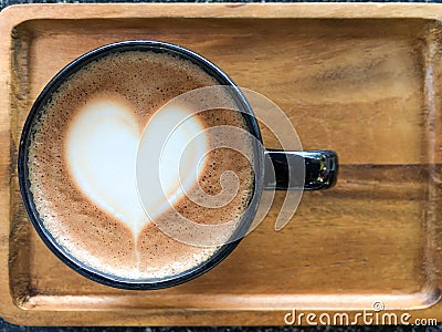 white heart shape hot mocha milk coffee in black round cup on wood tray with black stone background Stock Photo