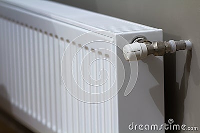 White heating radiator with thermostat valve on wall in an apartment interior after renovation works. Stock Photo