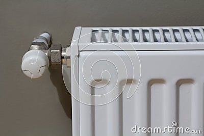 White heating radiator with thermostat valve on wall in an apartment interior after renovation works. Stock Photo