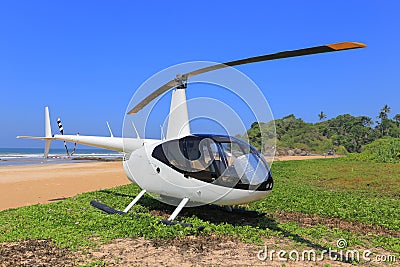 White helicopter Robinson R44 on the beach Stock Photo
