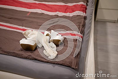 White high heels and Stay up stockings lie on a blanket on a bed Stock Photo