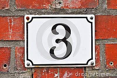 A white house number plaque, showing the number three, number 3 Stock Photo