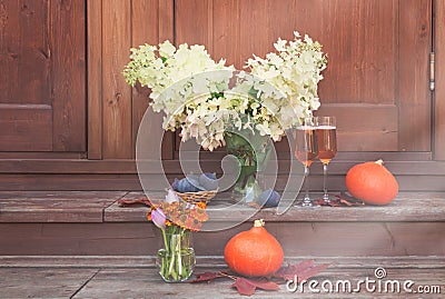 White hydrangea, glasses of rose champagne, helenium, autumn crocuses, figs and pumpkins are on steps of rustic wooden ladder Stock Photo