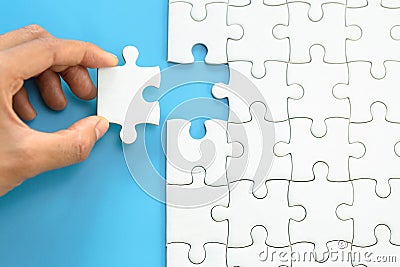 White jigsaw in the hands, The correct solution. Teamwork, Solving and completing the task. Last piece of jigsaw puzzle. Stock Photo