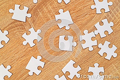 White jigsaw puzzle pieces scattered on wooden table Stock Photo