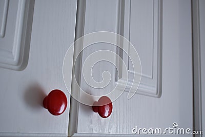 White kitchen cabinet with red knobs Stock Photo