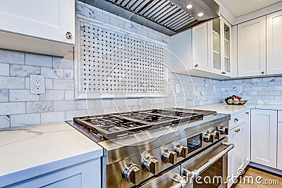 White Kitchen with stainless steel hood over gas cooktop. Stock Photo