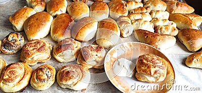 On the white kitchen table are poppy buns, patties, and a plate of sour cream. Stock Photo