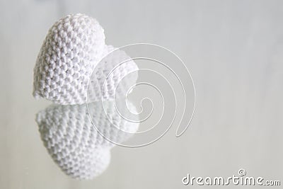 A white knitted heart is reflected in the mirror on a white background Stock Photo