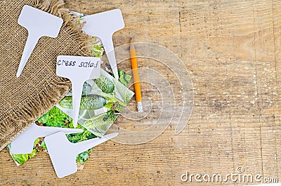 White labels-markers for plants lie on burlap, on wooden background. Stock Photo