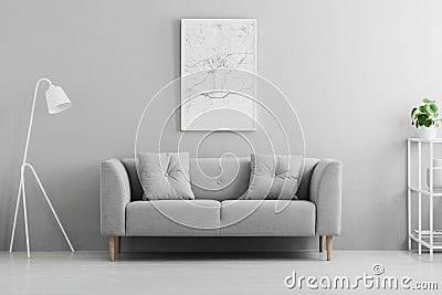 White lamp next to grey couch in minimal living room interior wi Stock Photo