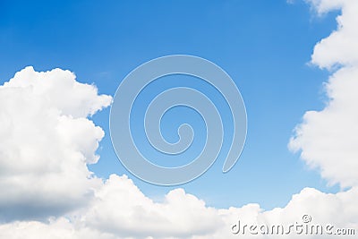 White large fluffy clouds frame a clear blue sky Stock Photo