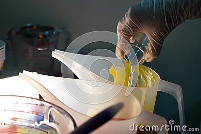 White latex gloved hand pouring a small beaker of liquid fragrance oil, water, chemical and more into a solution, food Stock Photo