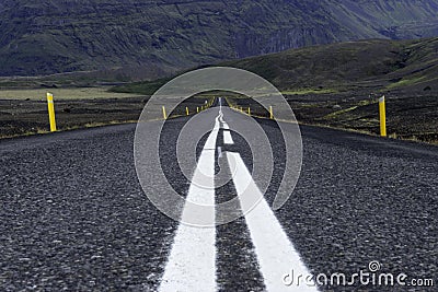 White leading lines in the middle of the road towards the green mossy mountains in Iceland. Stock Photo