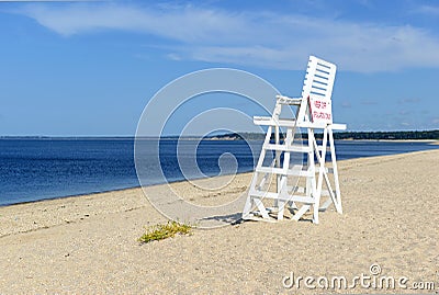 White lifeguard chair on empty sand beach with blue sky Stock Photo