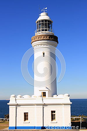 White lighthouse by blue sky and sea Stock Photo