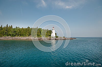 White lighthouse on rocky island lake side Stock Photo