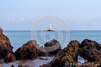 White Lighthouse Standing on The Rocks Stock Photo