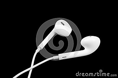 White little headphones isolated on black background. Earphones isolated on black background. Stock Photo