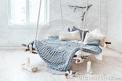 White loft interior in classic scandinavian style. Hanging bed suspended from the ceiling. Cozy large folded gray plaid Stock Photo