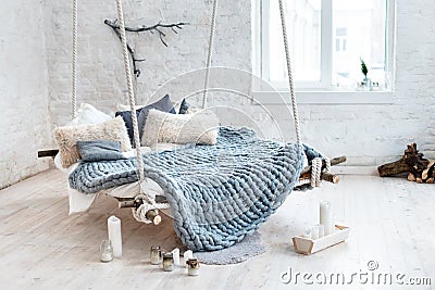 White loft interior in classic scandinavian style. Hanging bed suspended from the ceiling. Cozy large folded gray plaid Stock Photo