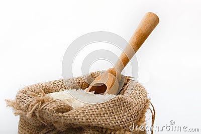 White long rice in burlap sack with wooden spoon Stock Photo