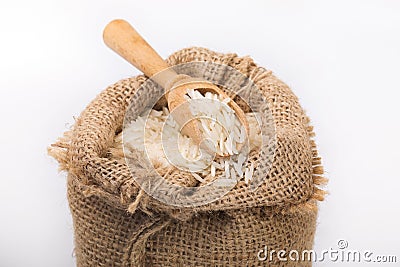 White long rice in burlap sack with wooden spoon Stock Photo