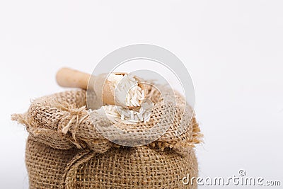 White long rice in burlap sack with wooden spoon Stock Photo