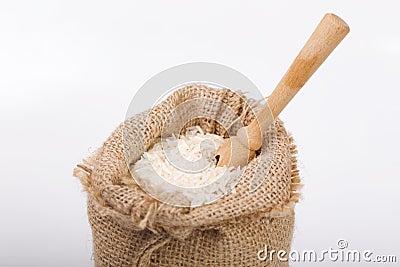 White long rice in burlap sack with wooden spoon Stock Photo