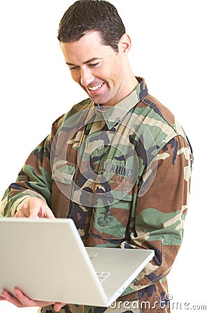 White male in army uniform on lap top smiling Stock Photo
