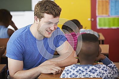 White male Volunteer teacher helping boy in elementary school class Stock Photo