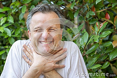 A white man makes a funny face while clutching his neck with his hands as if he wanted to choke Stock Photo