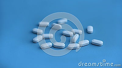 white medicinal pills isolated on the blue background Stock Photo