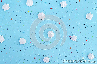 White meringues and colorful confetti on blue background. Stock Photo