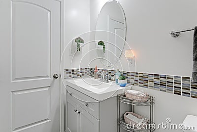 White Minimal Bathroom Interior with Multi Colored Accent Tiles and Small Sink Vanity with Oval Mirror Stock Photo